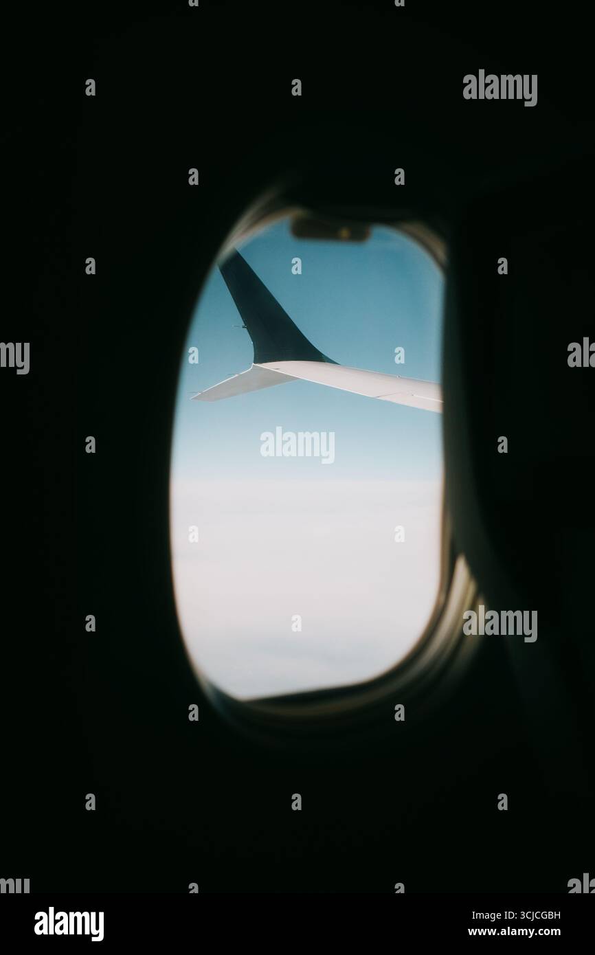 Vue d'une fenêtre d'avion montrant l'aile de l'avion contre un ciel bleu clair. L'image capture le sens du voyage et l'expérience de voler un Banque D'Images