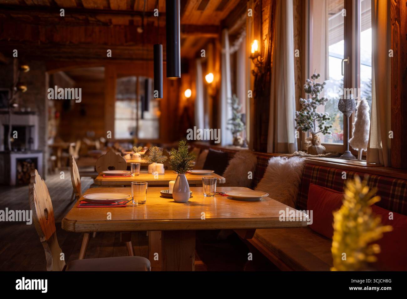 Un intérieur accueillant de restaurant alpin autrichien, présentant un décor rustique, un éclairage chaleureux et le charme hivernal. Le mobilier en bois reflète l'Europe authentique Banque D'Images