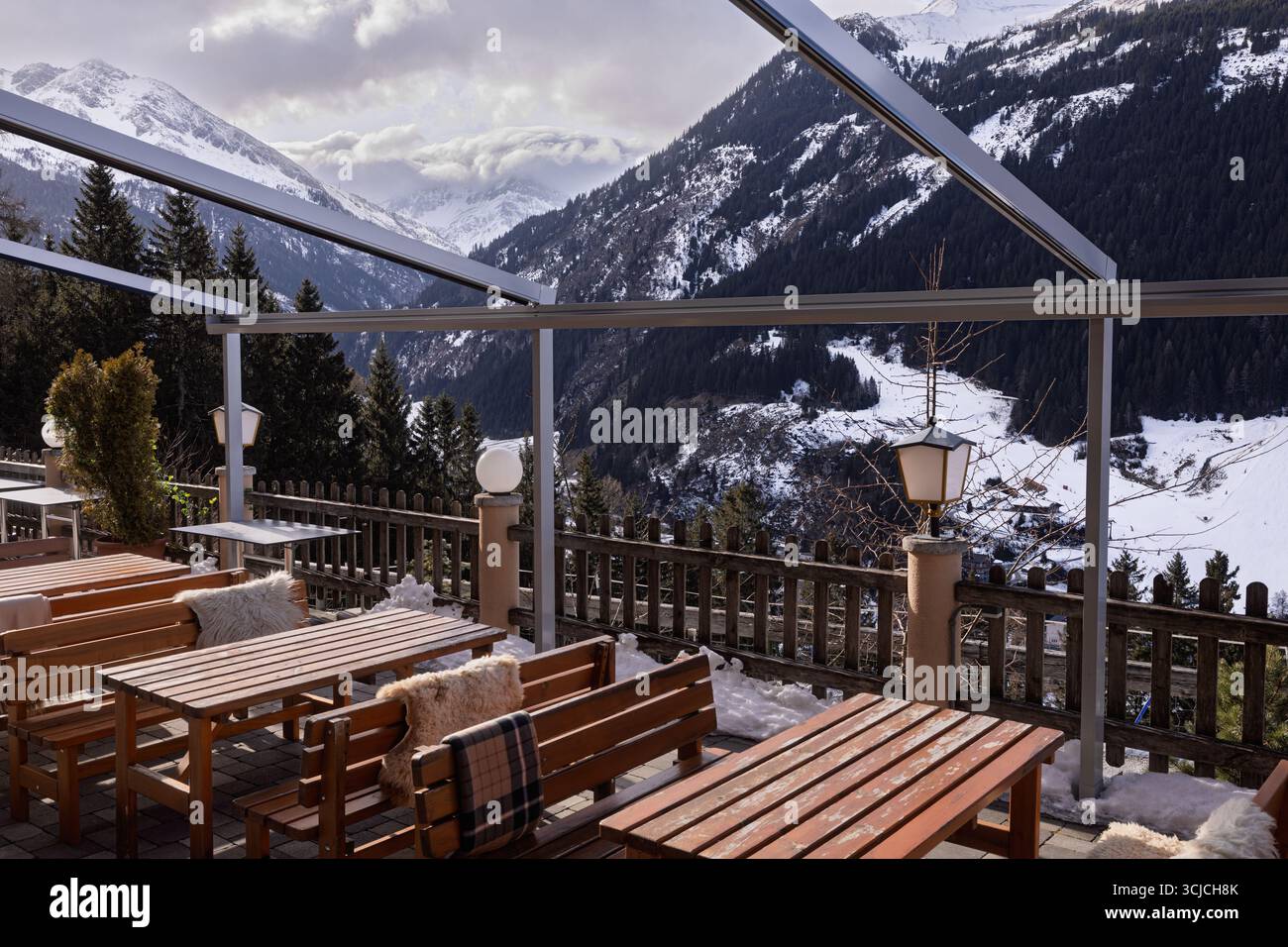 Un restaurant alpin serein en Autriche, doté de tables en bois et de touches chaleureuses, surplombe les montagnes enneigées. Parfait pour profiter de l'hiver » Banque D'Images