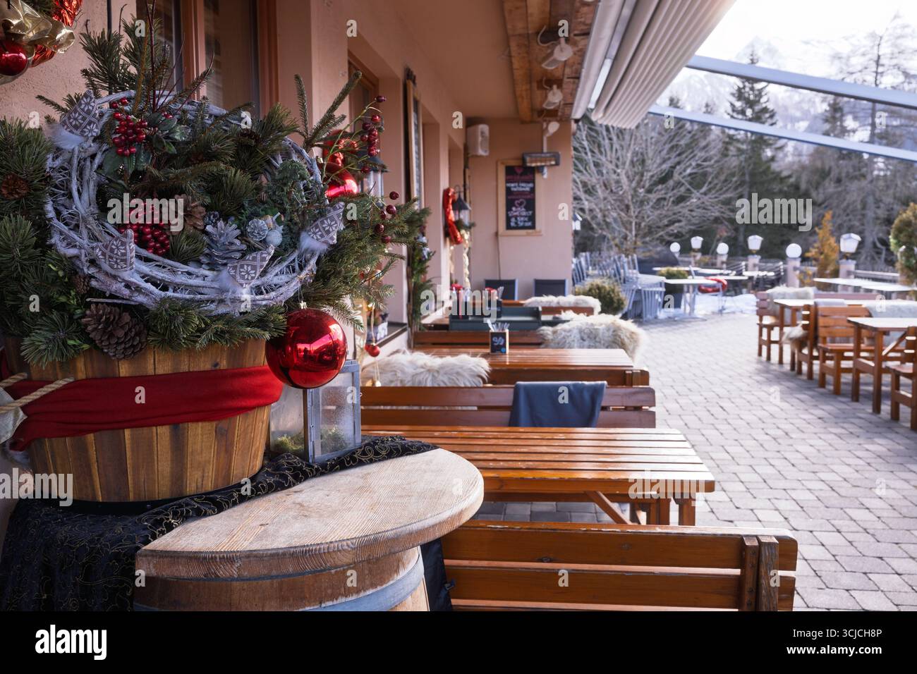 Entrée à un restaurant alpin autrichien magnifiquement décoré pour Noël. Des tables en bois, des couronnes festives et un environnement enneigé créent un inviti Banque D'Images
