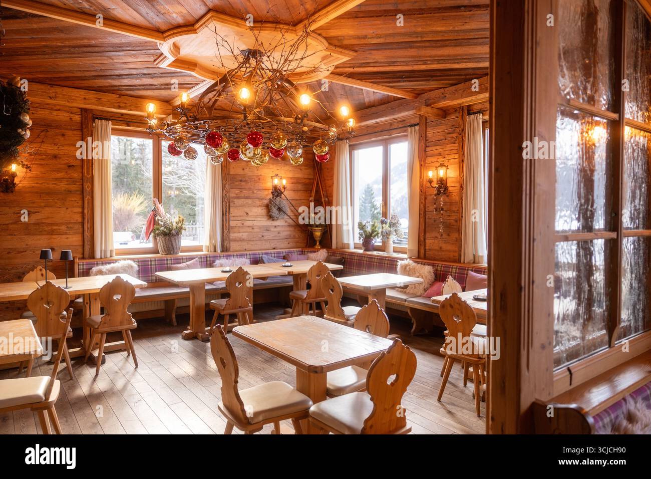Charmant intérieur de restaurant alpin en Autriche en hiver, avec un design rustique en bois, des décorations festives et de grandes fenêtres donnant sur la neige Banque D'Images