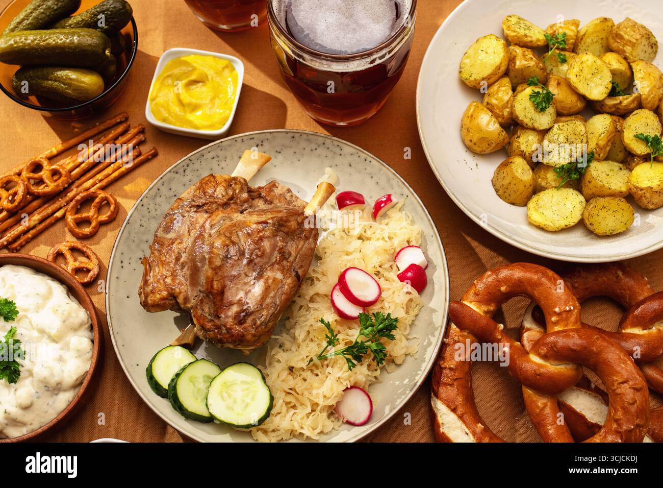 Vue de dessus d'une cuisine traditionnelle allemande avec jarret de porc accompagné de choucroute et de concombres, pommes de terre rôties, bretzels bavarois et cornichons Banque D'Images