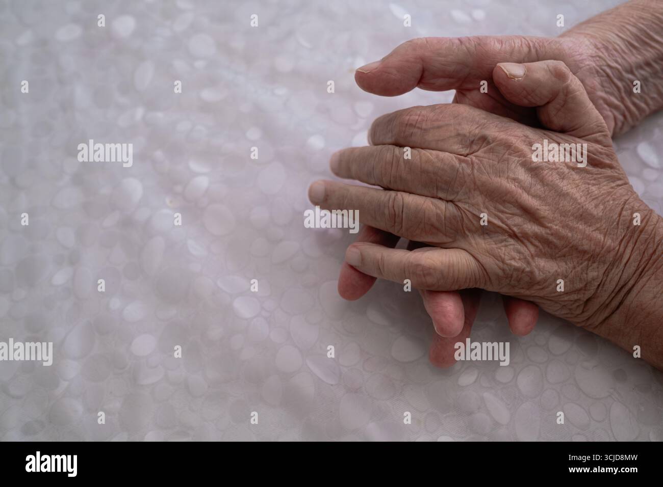 Homme âgé éprouvant des tremblements dans ses mains, soulignant les défis des maladies neuromusculaires et des troubles neurologiques dans la vieillesse. Banque D'Images