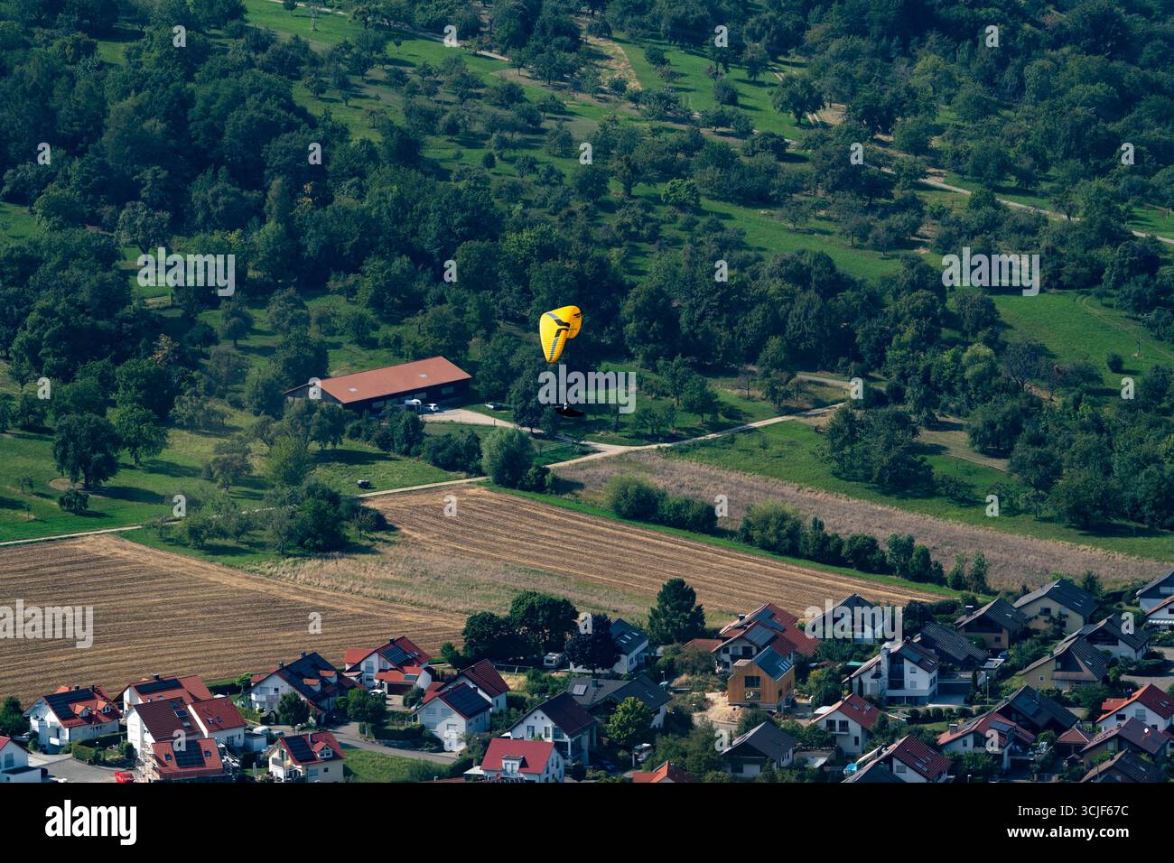 Parapente descendant au-dessus d'un village rural près de Breitenstein, Allemagne Banque D'Images
