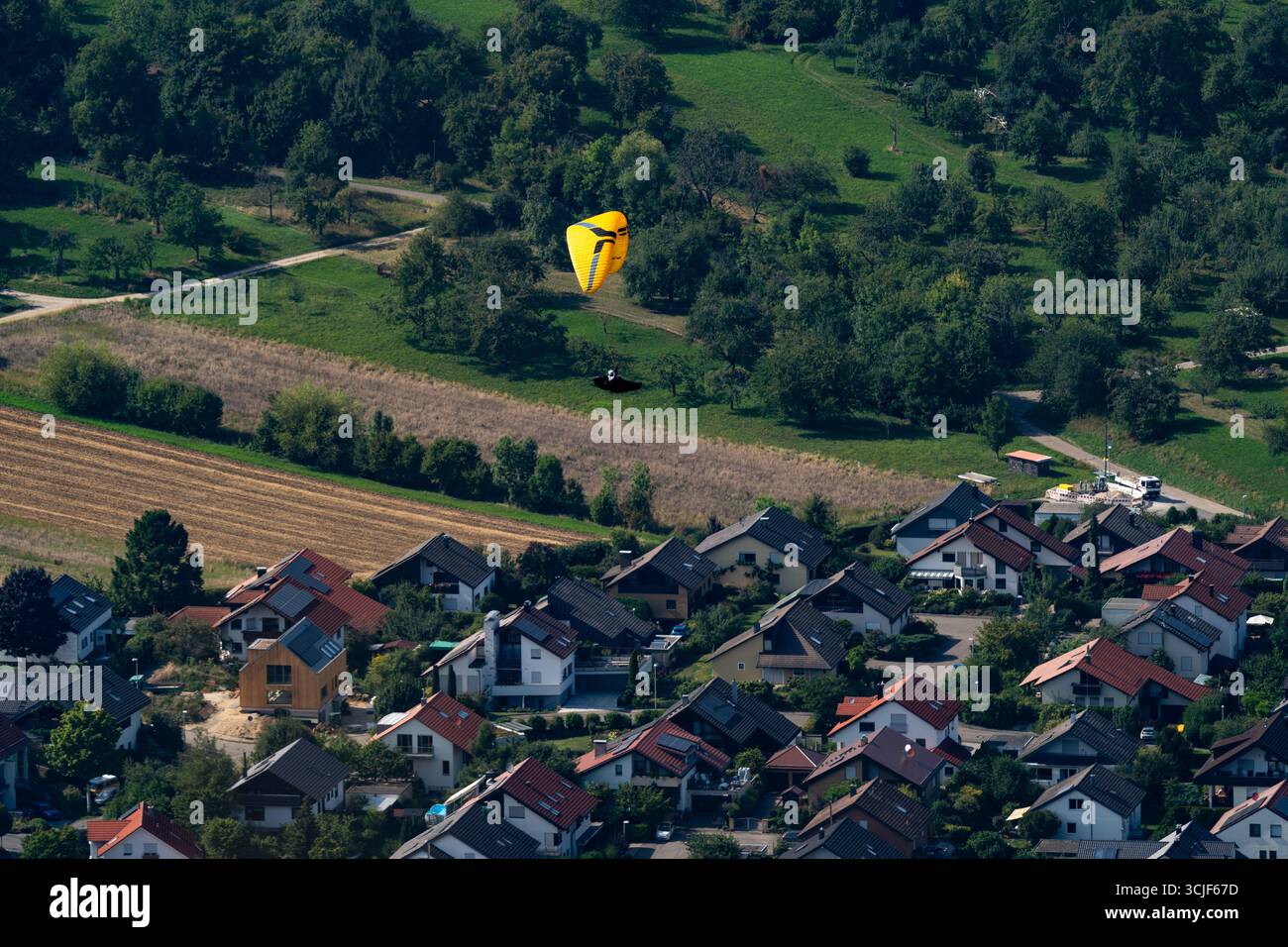 Parapente descendant au-dessus d'un village rural près de Breitenstein, Allemagne Banque D'Images