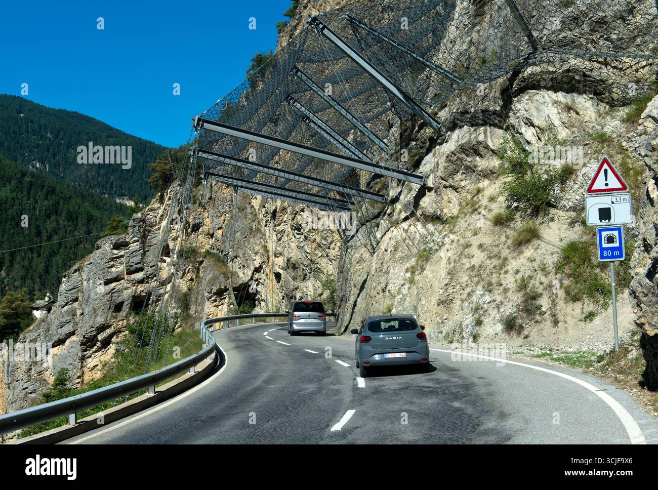 Voitures roulant sous des filets de sécurité sur la route les Pontis, Val d'Anniviers, Valais, Suisse Banque D'Images
