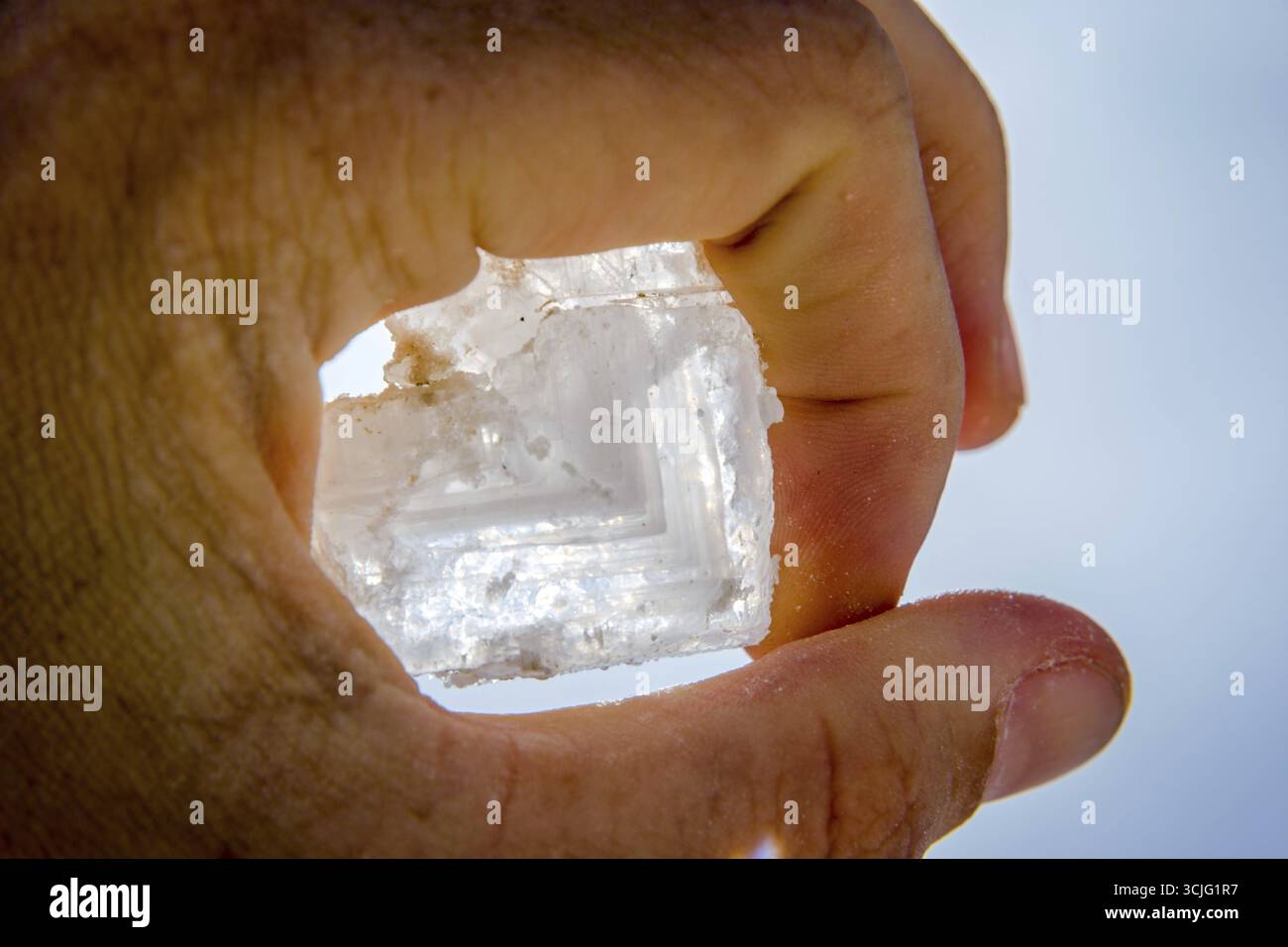 En cristal de sel gros dans la main contre le ciel bleu Banque D'Images