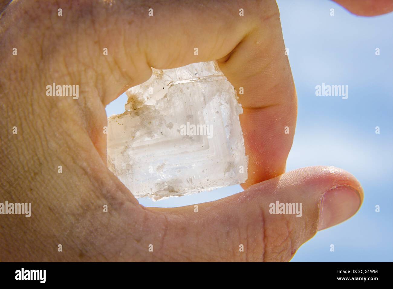 En cristal de sel gros dans la main contre le ciel bleu Banque D'Images
