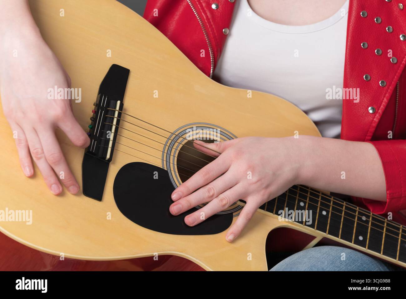Vue rapprochée du corps de la guitare et des mains de la guitariste en position détendue pendant la pause dans la performance Banque D'Images