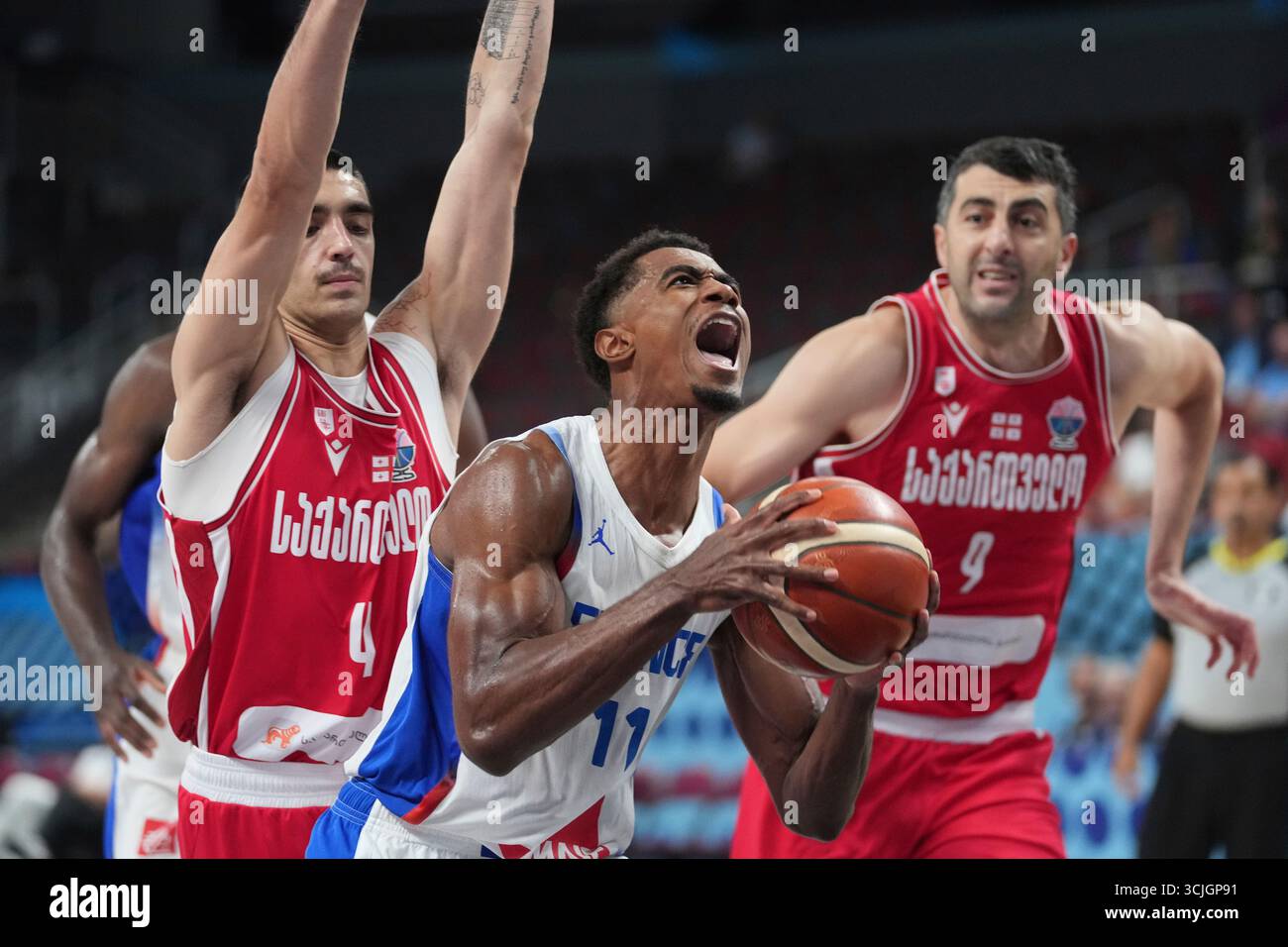 France's Theo Maledon, centre, drives between Georgia's Rati Andronikashvili, left, and Georgia's Giorgi Shermadini during the Eurobasket, European Basketball Championship round of 16 match between France and Georgia at the Riga Arena in Riga, Latvia, Sunday, Sept. 7, 2025. (AP Photo/Sergei Grits) Banque D'Images