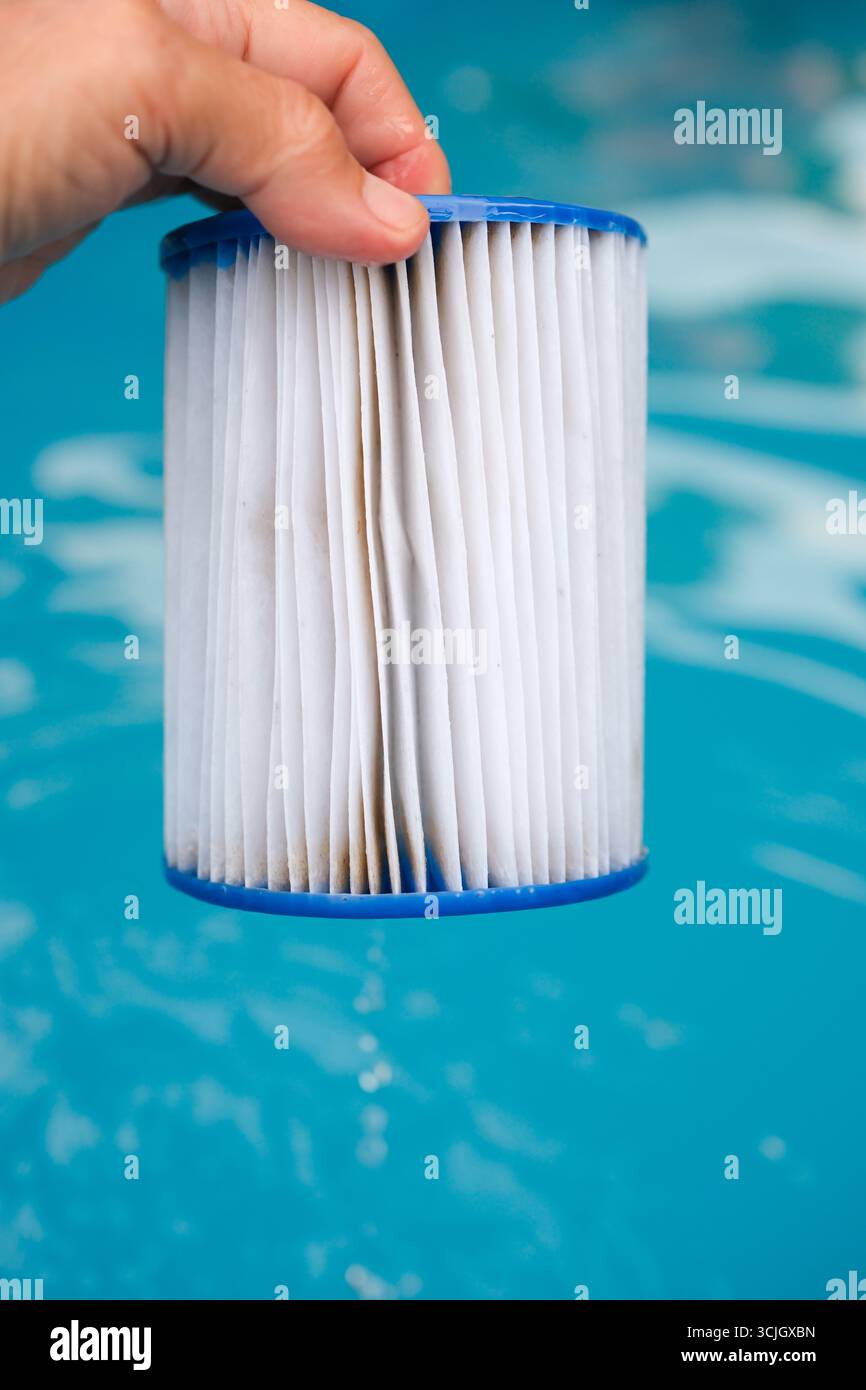 Cartouche filtrante de piscine de remplacement dans la main d'une femme. L'eau s'écoule dans le filtre humide. Réutilisation du filtre. Banque D'Images
