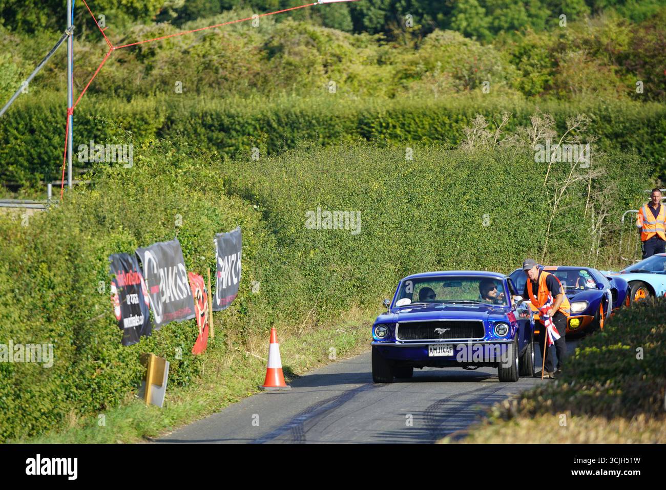 Rallye de voitures classiques sur la route rurale avec les participants et les maréchaux en plein jour. Shere Hill Climb, East Clandon, Guildford Banque D'Images