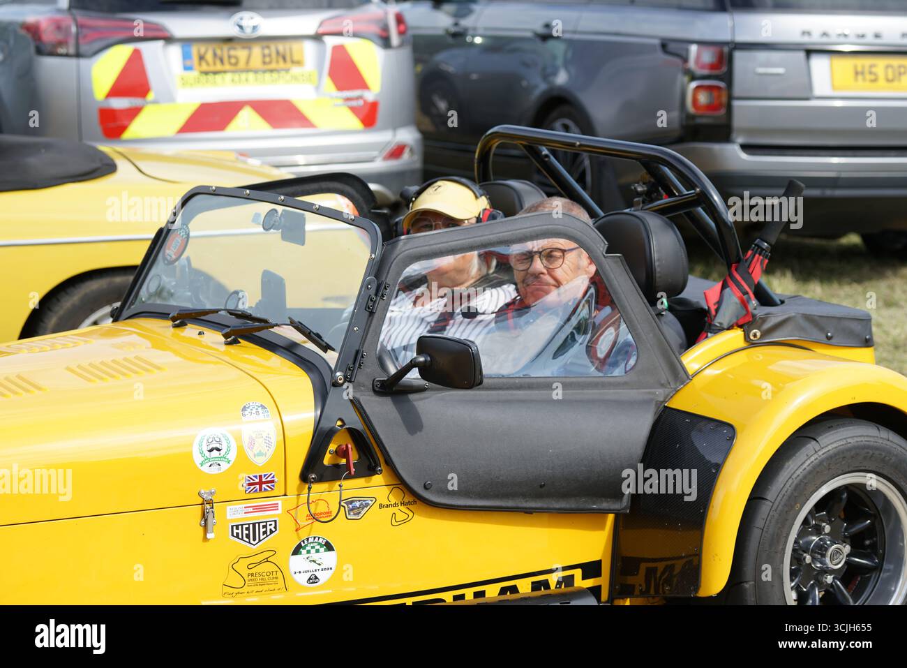 Voiture de sport jaune avec deux personnes assises à un événement extérieur. Shere Hill Climb, East Clandon, Guildford Banque D'Images