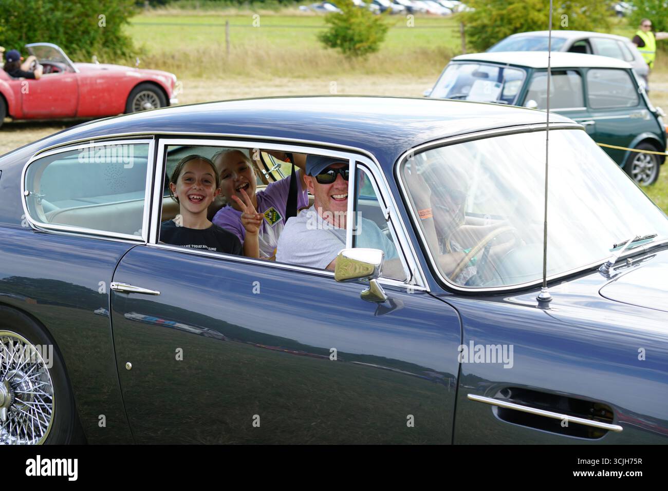 Famille profitant d'une balade en voiture classique à un salon de voitures anciennes. Shere Hill Climb, East Clandon, Guildford Banque D'Images