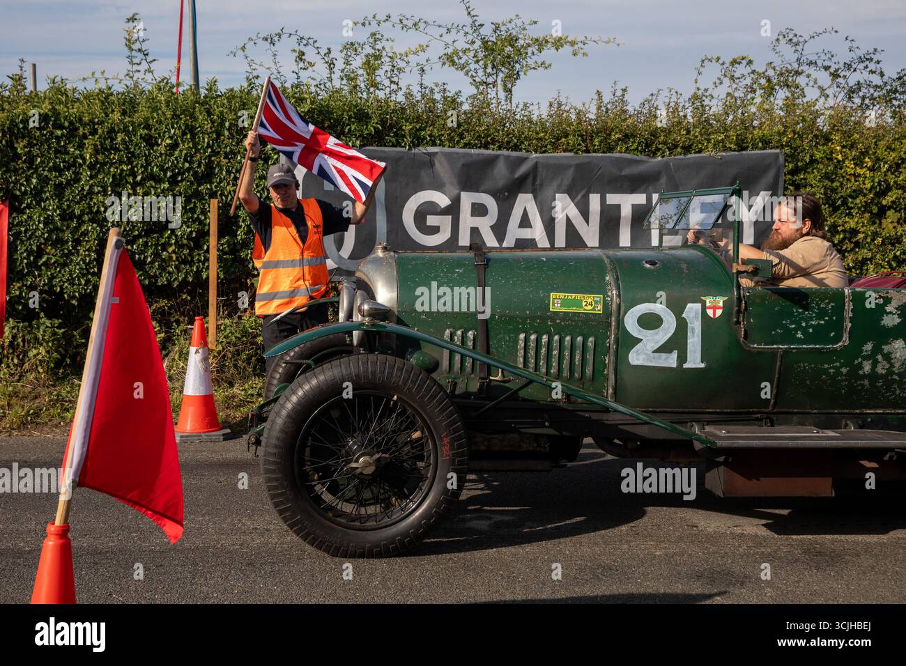 Guilford, Royaume-Uni. 07 septembre 2025. Un démarreur agite un drapeau pour libérer une Bentley classique sur une montée en colline. La 13e ascension de Shere Hill a attiré des centaines de passionnés d'automobile. Cet événement automobile annuel met en vedette des participants du public conduisant des véhicules standard, ainsi que des propriétaires de voitures de course, classiques et supercars, qui concourent sur une voie publique fermée pour obtenir le meilleur temps contre la montre. Outre la montée de la colline, les concurrents et les spectateurs ont eu la chance de voir les voitures concurrentes dans la grande zone de paddock à la ligne de départ du parcours. Crédit : SOPA images Limited/Alamy Live News Banque D'Images
