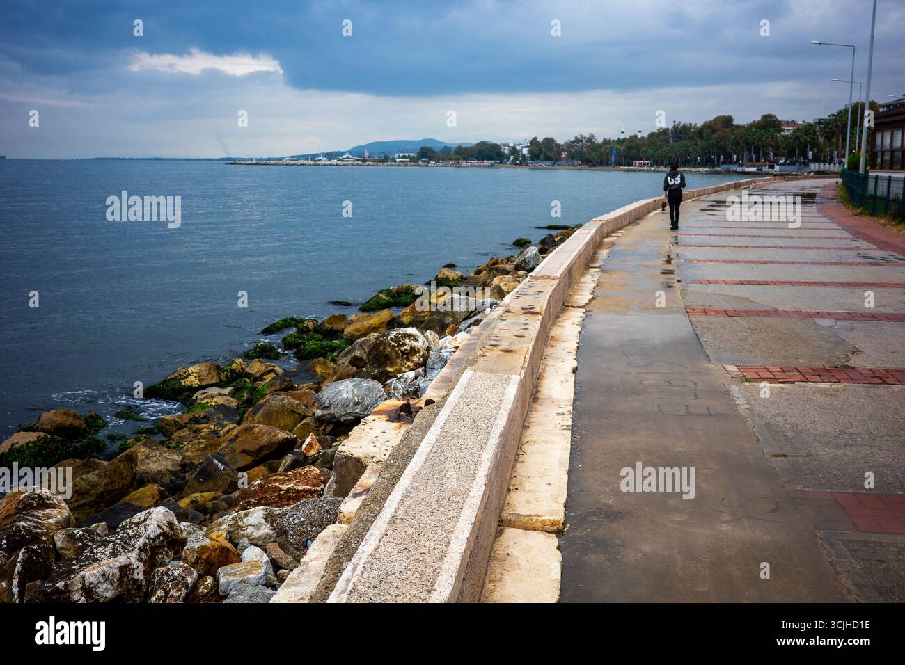Une personne marche le long d'une promenade en bord de mer à côté d'un rivage rocheux par une journée couverte à Yalova, Turquie. Yalova, province de Yalova, Turquie – 0 septembre Banque D'Images