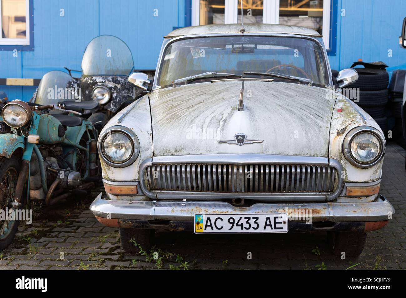 Wroclaw, Pologne - août 28 2025 : vue de face de gaz Volga soviétique altérée et vieille moto Banque D'Images