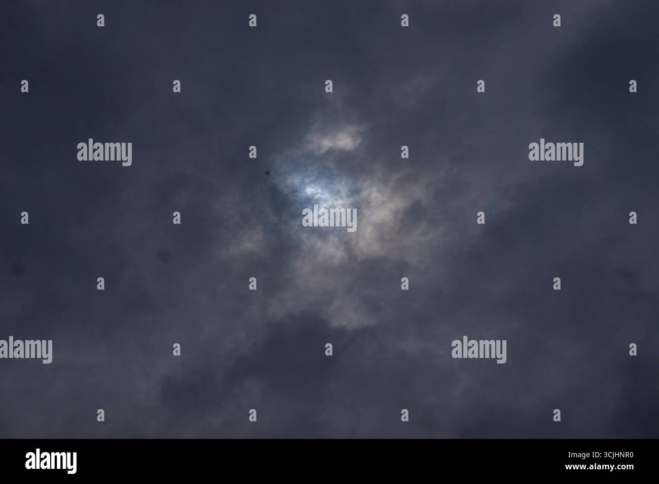 Soleil caché dramatique regardant faiblement à travers d'épais nuages de pluie sombre par temps orageux Banque D'Images