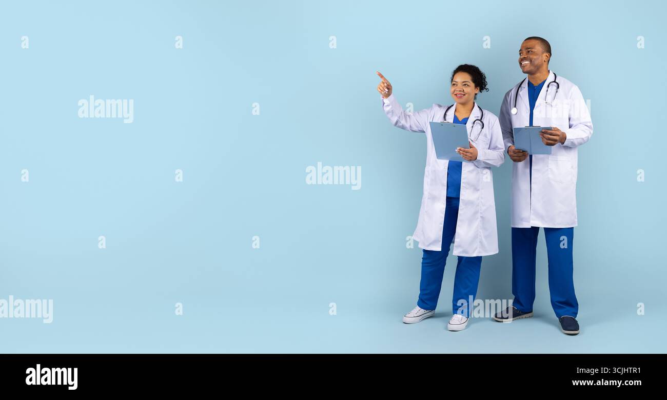 Deux professionnels de la santé afro-américains en studio pointant de côté l'espace de copie Banque D'Images