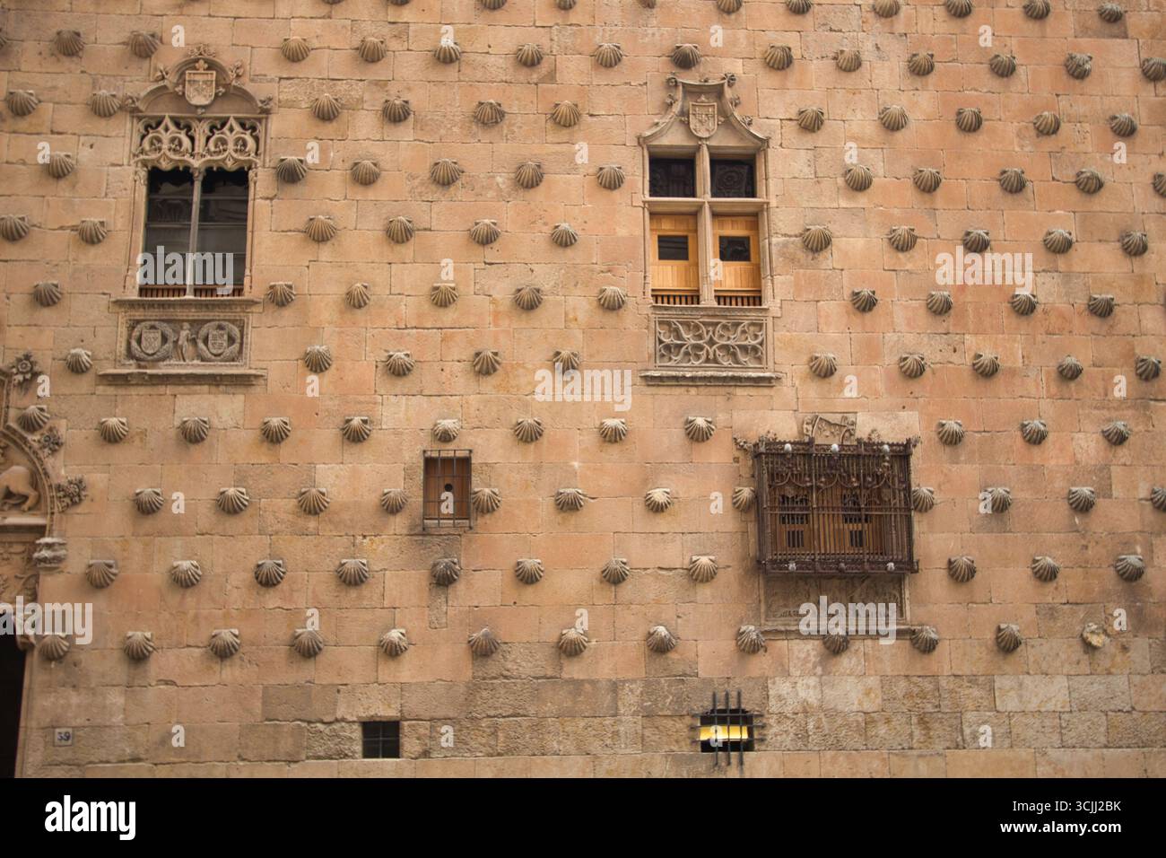 Façade avec des coquillages à Casa de las Conchas : mur de grès historique avec des coquilles Saint-Jacques et grille de fenêtre ornée dans la célèbre Casa de las Conc de Salamanque Banque D'Images