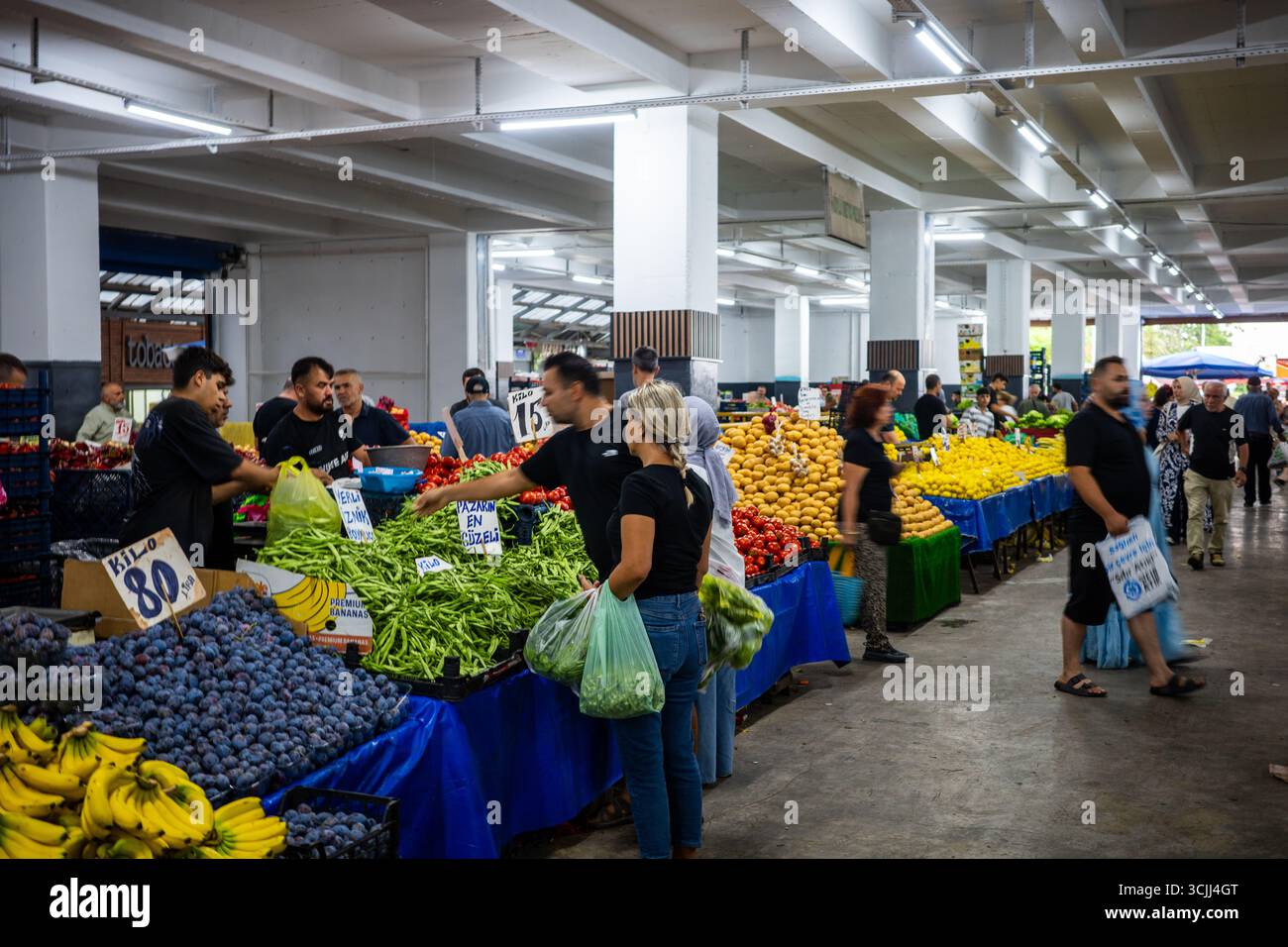 Les gens achètent des fruits et légumes frais dans un marché couvert à Yalova, en Turquie. Les stalles sont remplies de prunes, de bananes, de poivrons, de tomates et autres Banque D'Images