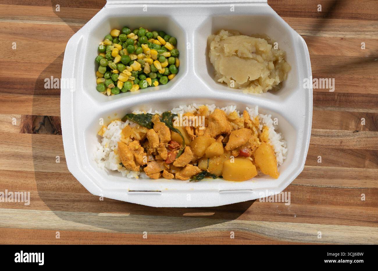 Récipient en polystyrène avec trois compartiments séparant les aliments. Contenant du maïs et des pois, de la citrouille et l'autre ragoût de poulet et de riz. Concept pour fe Banque D'Images