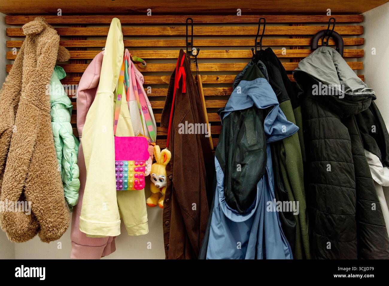Vestes d'extérieur d'automne et manteaux suspendus sur des cintres dans une armoire en bois dans le couloir Banque D'Images