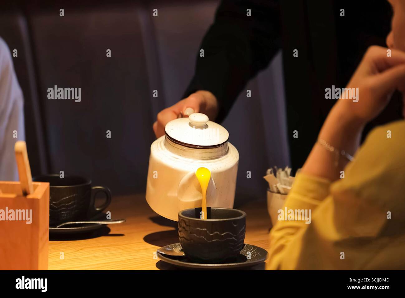 Serveur versant le jus d'orange d'une théière en émail dans une tasse Banque D'Images
