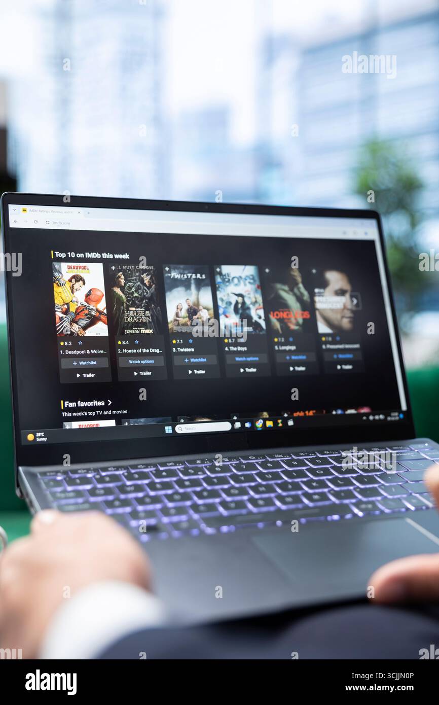 Bucarest, Roumanie - 30 juillet 2024 - Top 10 des films à succès sur IMDb, jeune homme lisant les critiques et regardant le casting avant de choisir un film à regarder. Cinéphile au bureau. Banque D'Images