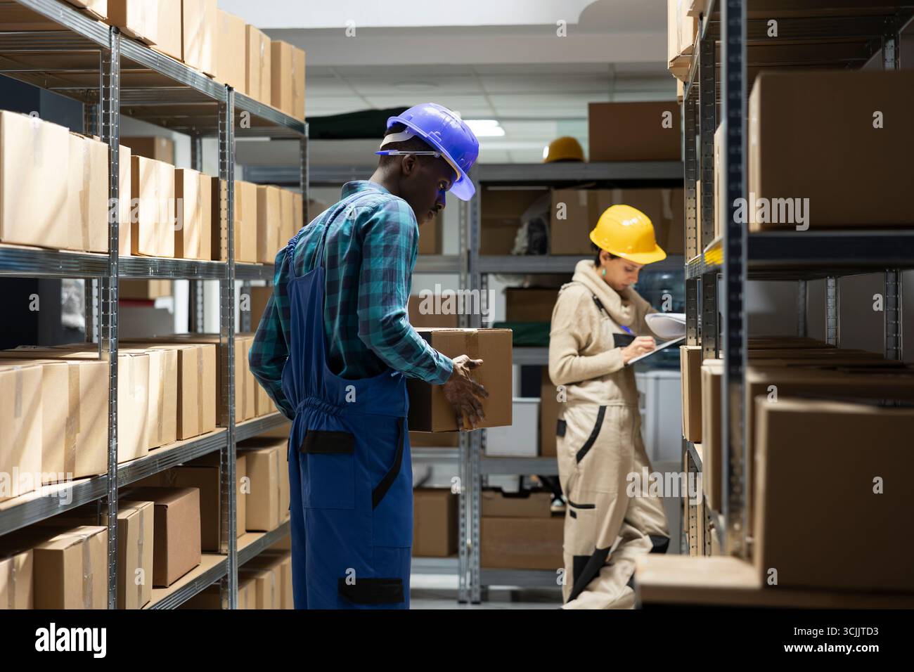 Environnement d'entrepôt axé sur l'efficacité de la chaîne d'approvisionnement et le stockage. L'employé noir gère les tâches manuelles telles que le suivi des stocks, la manutention des marchandises et la préparation des expéditions. Banque D'Images