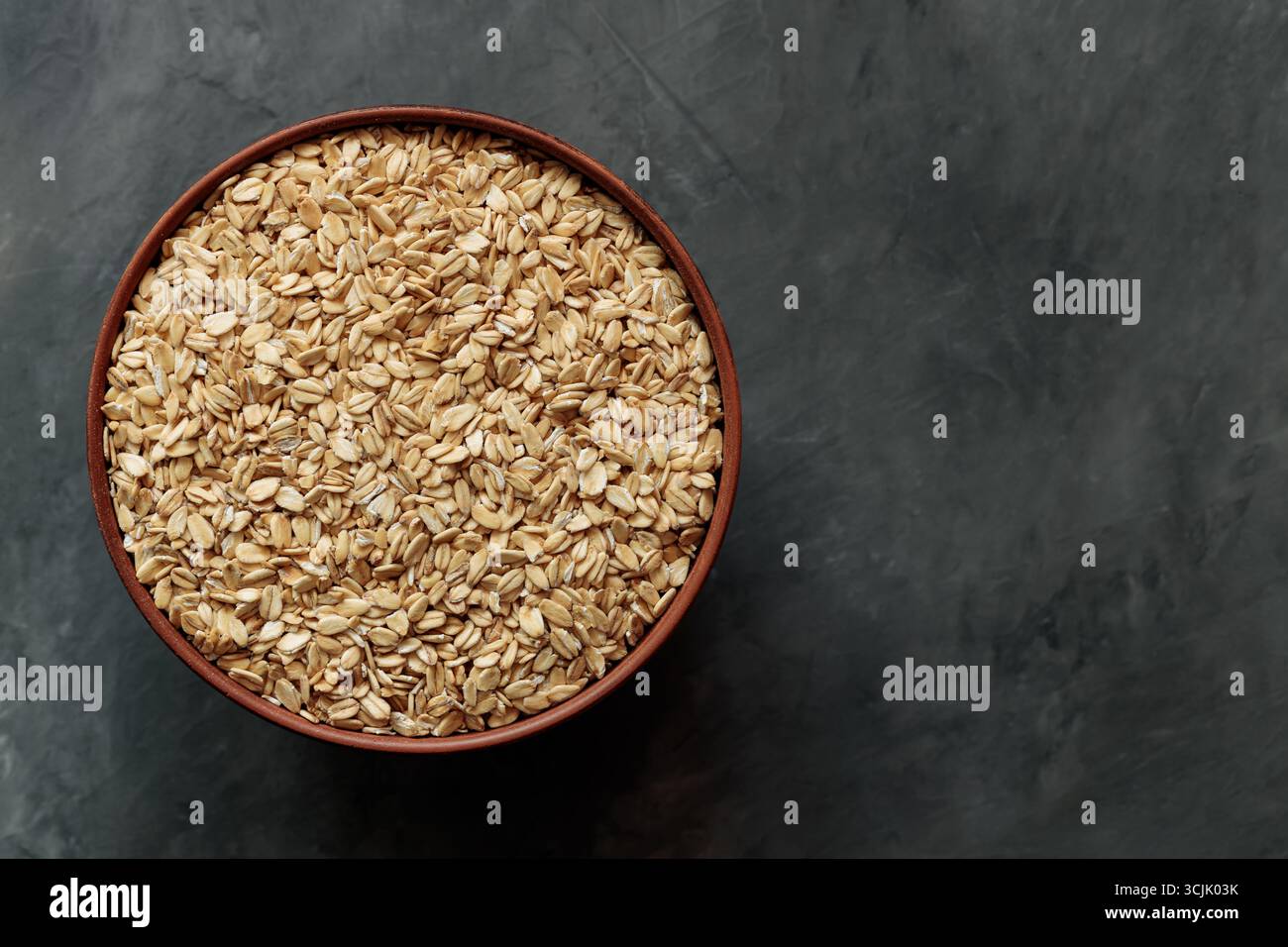 Flocons d'avoine dans un bol en céramique sur un espace de copie de surface grise Banque D'Images