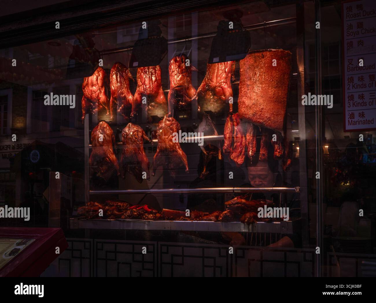 Diverses viandes sur une broche accrochée dans une vitrine d'un restaurant chinois et boucher à Chinatown dans le district de Soho, Londres, Angleterre, Royaume-Uni Banque D'Images
