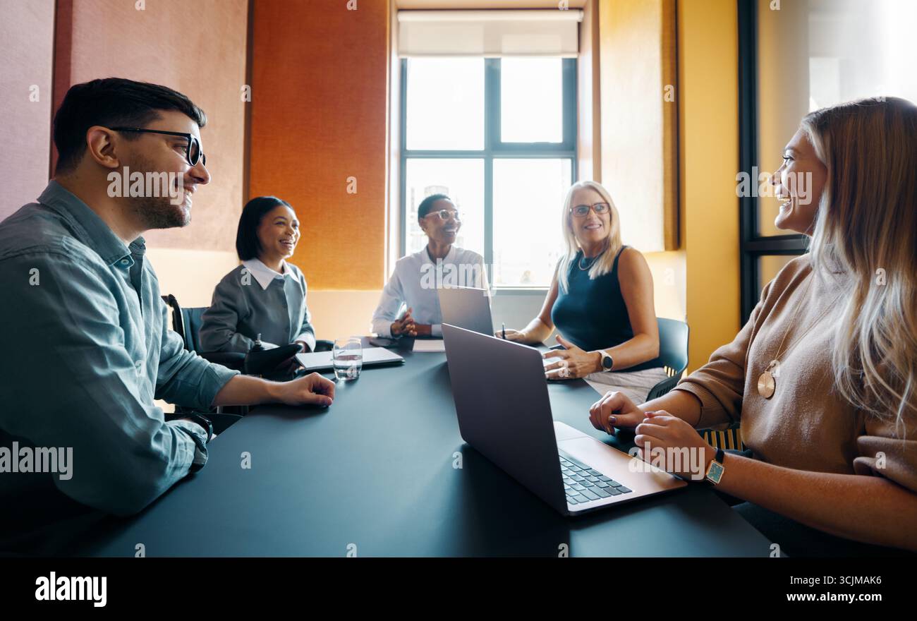 Un groupe de professionnels des affaires de différents âges et sexes engagés dans une discussion productive sur l'espace de travail. Travail d'équipe dans un environnement de bureau moderne, Banque D'Images