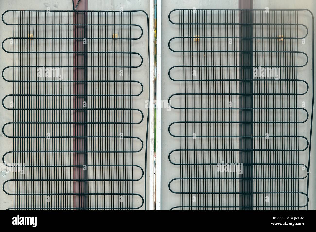 Serpentins de condenseur de grille métallique sur le panneau arrière du réfrigérateur, montrant la structure industrielle et le détail fonctionnel du système de refroidissement, en gros plan Banque D'Images