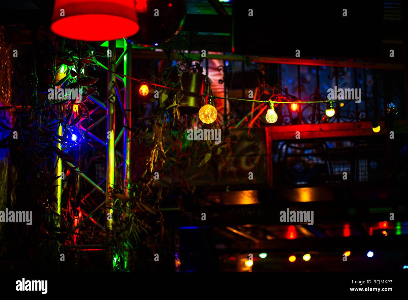 Des lampes lumineuses chaudes et des décorations suspendues colorées créent une ambiance nocturne animée dans un bar ou un club. Banque D'Images