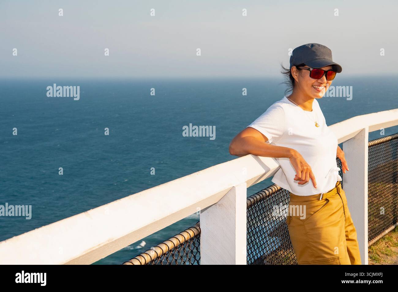 Femme penchée désinvolte contre une clôture au cap Byron Banque D'Images