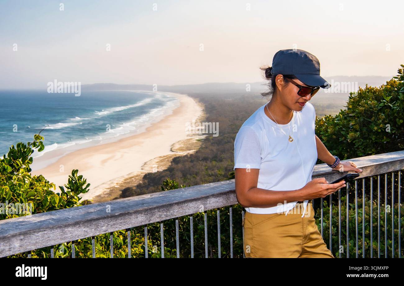 Belle femme textant sur son téléphone portable à Viewpoint à Byron Bay Banque D'Images