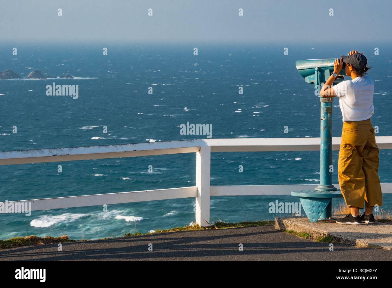 Femme regardant à travers des jumelles de point de vue à Cape Byron Banque D'Images