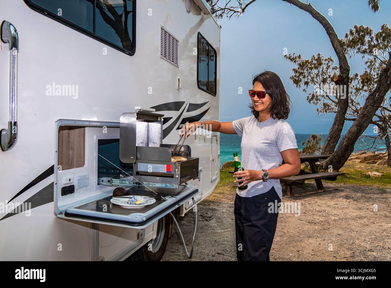 Femme barbecue sur barbecue à gaz sur le côté de son camping-car Banque D'Images