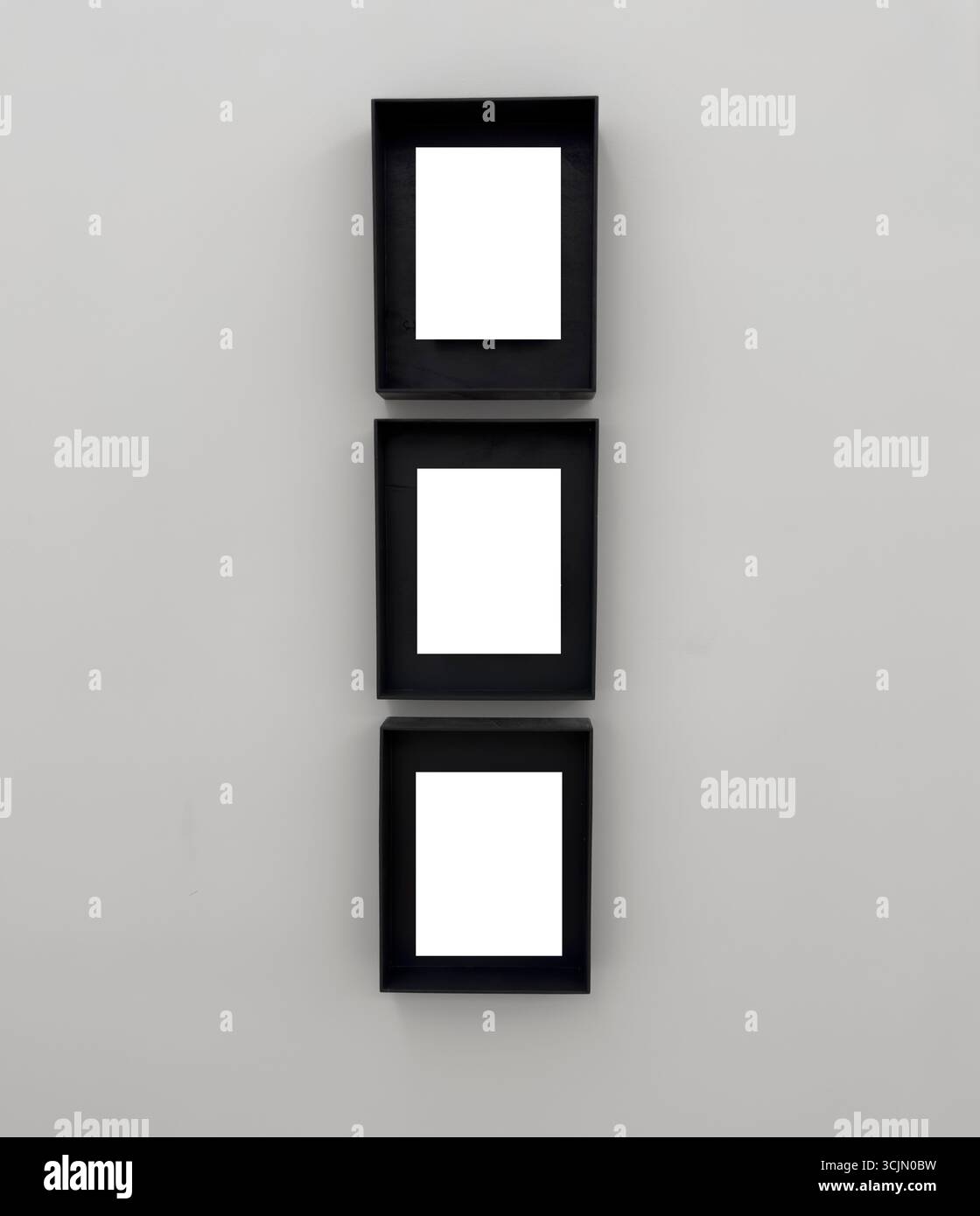 Trois cadres noirs verticaux disposés en colonne sur un mur lumineux. Les cadres sont profonds, ressemblant à des boîtes d'affichage, triptyque ou un pla d'artistes curated Banque D'Images