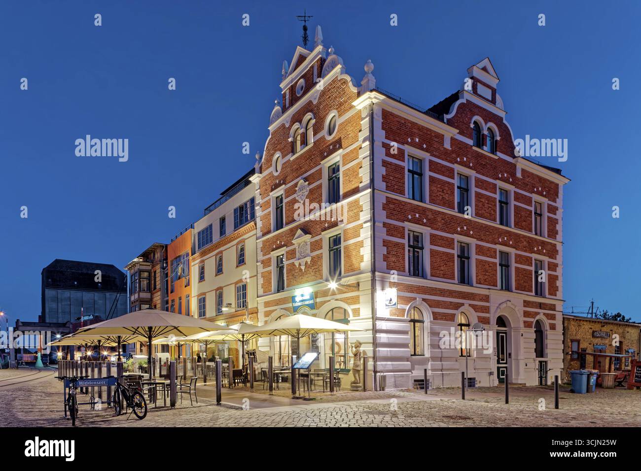 Vue de nuit, magnifique bâtiment avec sièges extérieurs et parasol, construit en 1889, Hiddenseer Hafenrestaurant und Hotel, Hafenstrasse 12B, port isl Banque D'Images