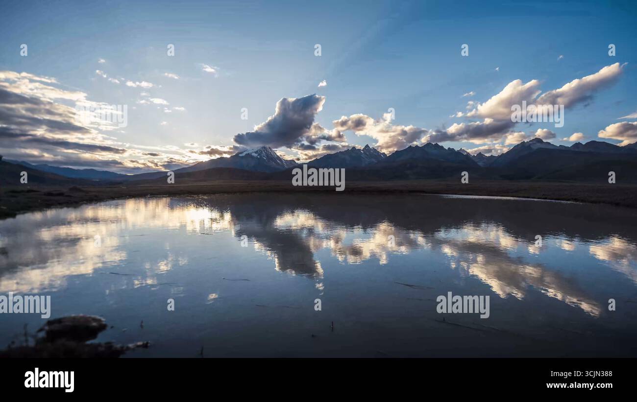 Montagnes ensoleillées et nuages reflétés dans un lac Banque D'Images