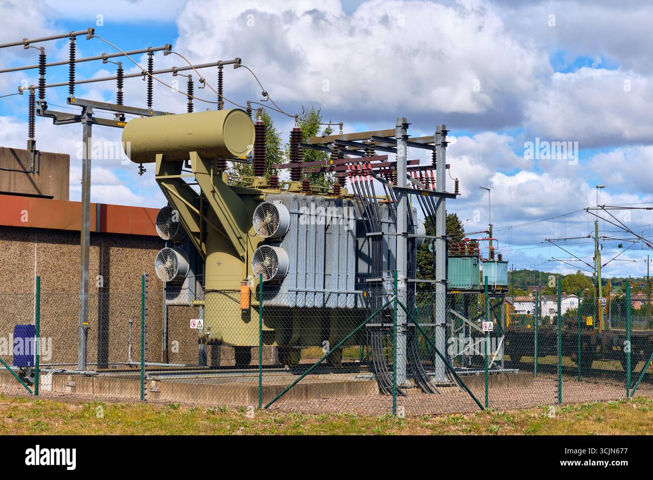 Grande sous-station de transformation électrique avec ventilateurs de refroidissement et lignes électriques situées le long des voies ferrées dans une zone industrielle de Halmstad, Suède. Banque D'Images