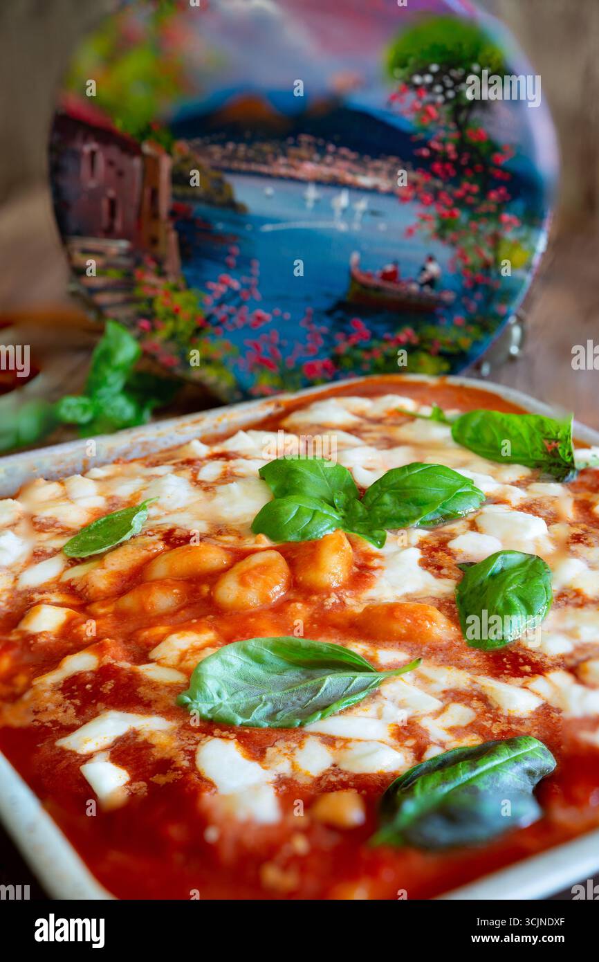 Gnocchi alla sorrentina cuit dans une poêle, avec basilic frais, tomates cerises et sauce tomate riche, incarnant la cuisine napolitaine traditionnelle Banque D'Images
