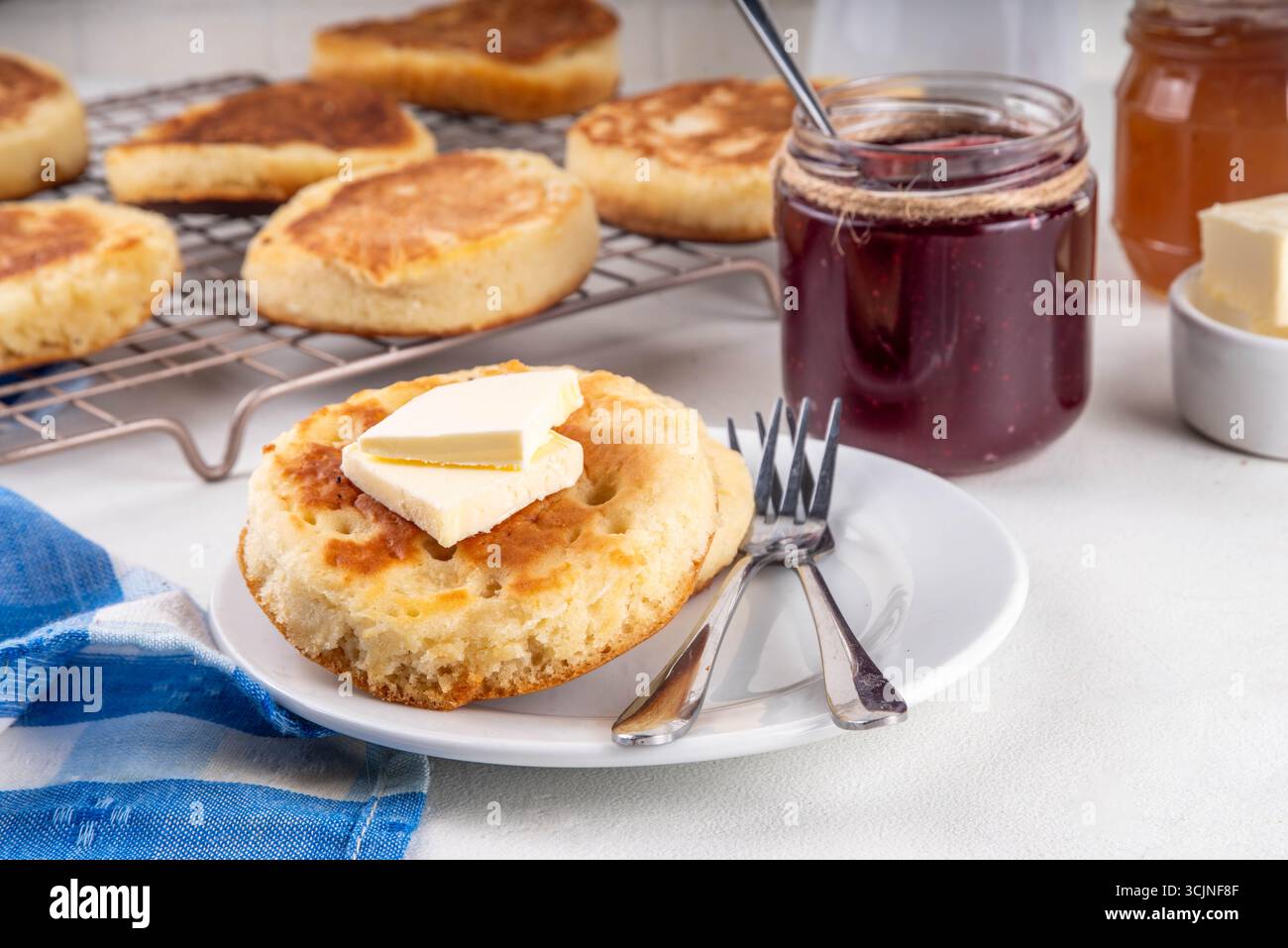 Crumpets de pâtisserie frit à la poêle anglaise traditionnelle, populaire en Angleterre, crêpes britanniques. Crumpets chauds sucrés empilent avec du beurre fondant et ja Banque D'Images