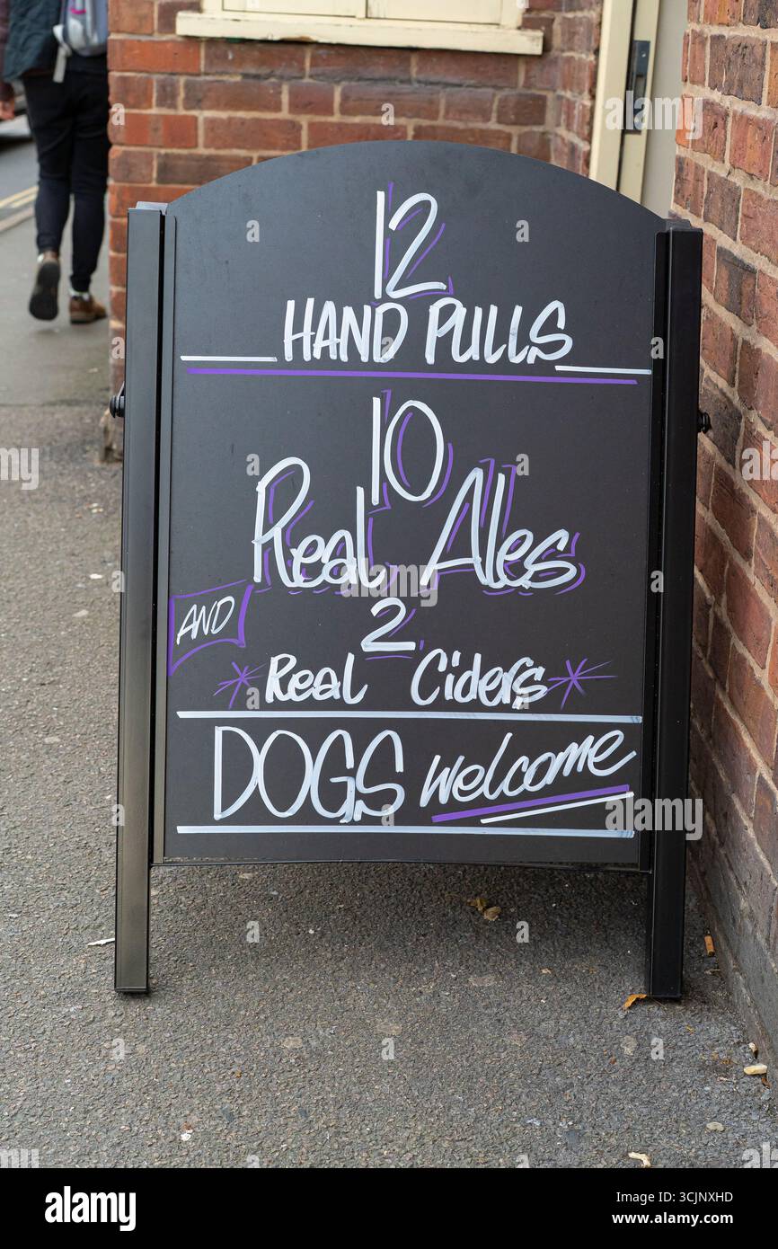 Panneau de chaussée a-board à l'extérieur d'une maison publique du Royaume-Uni annonçant 12 TIRS À LA MAIN : 10 VRAIES BIÈRES, 2 VRAIS CIDRES et CHIENS BIENVENUS. Banque D'Images