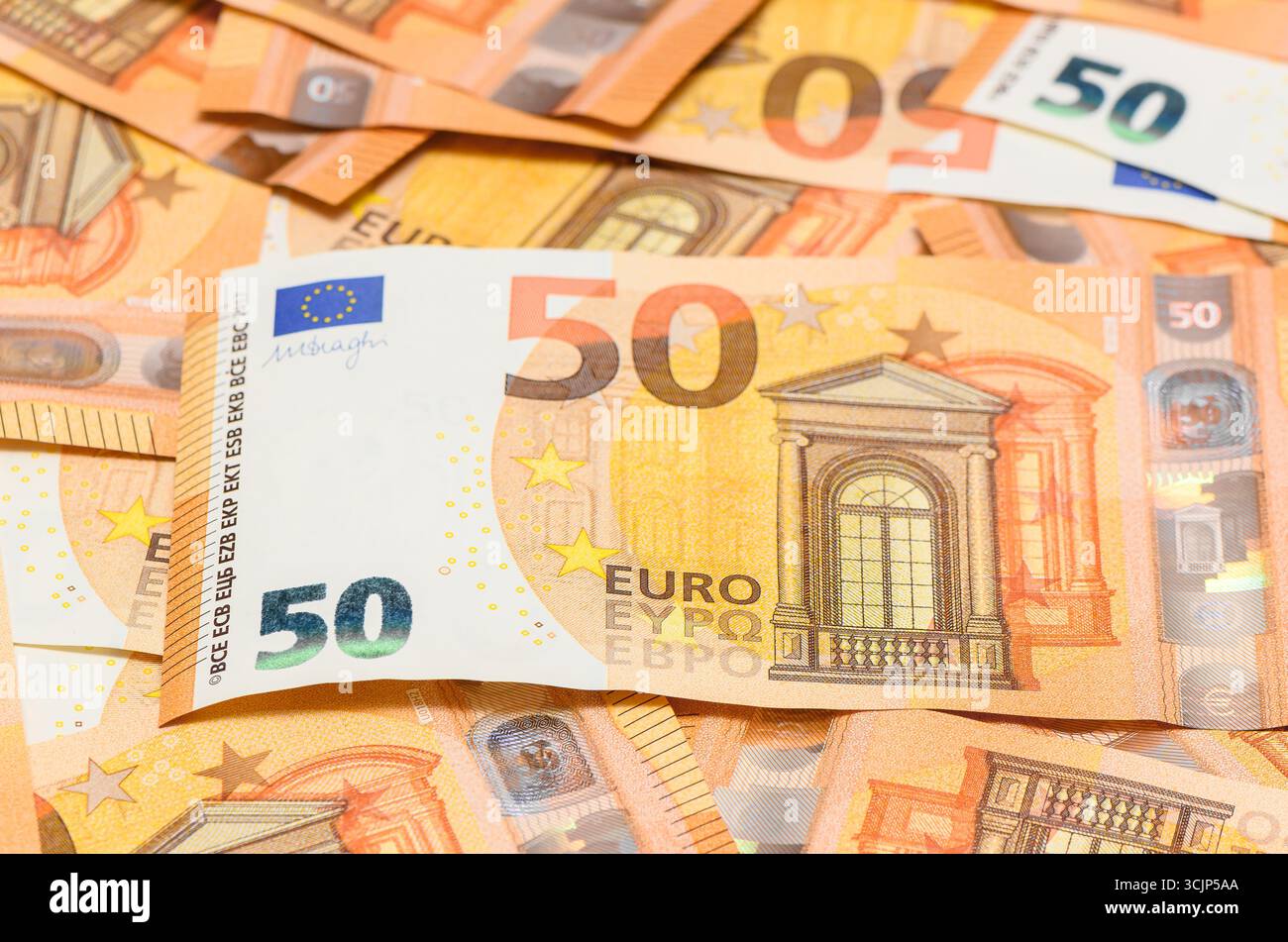 Vue rapprochée de cinquante billets en euros dispersés sur la table comme arrière-plan financier, symbole de la monnaie, de l'économie et des affaires. Banque D'Images