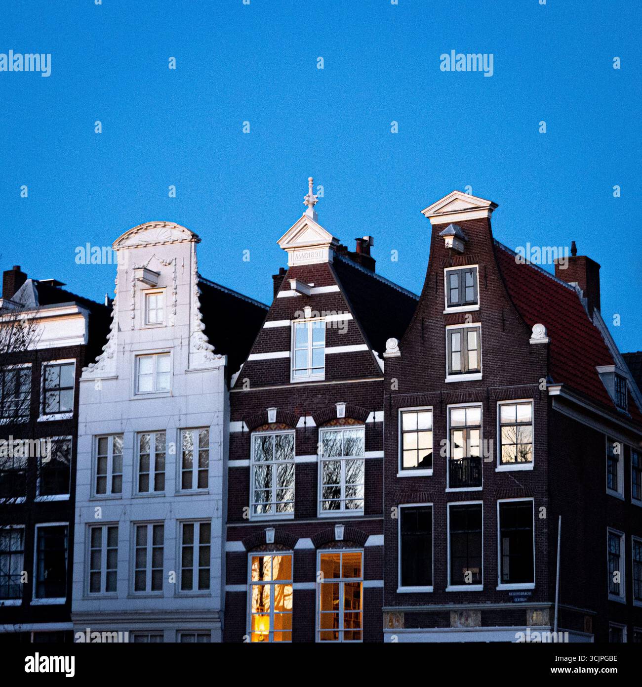 Maisons de canal hollandaises traditionnelles avec façades étroites et toits à pignons sous un ciel clair du soir. Banque D'Images