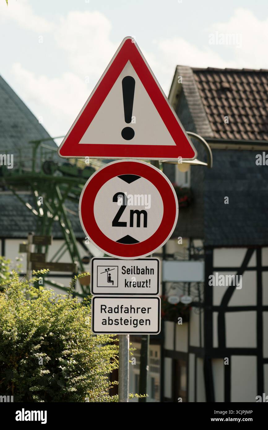 Avertissement exclamation hauteur limite passage du téléphérique les cyclistes descendent. Panneaux de signalisation routière multiples, y compris un panneau d'avertissement général, une restriction de hauteur de 2 mètres Banque D'Images
