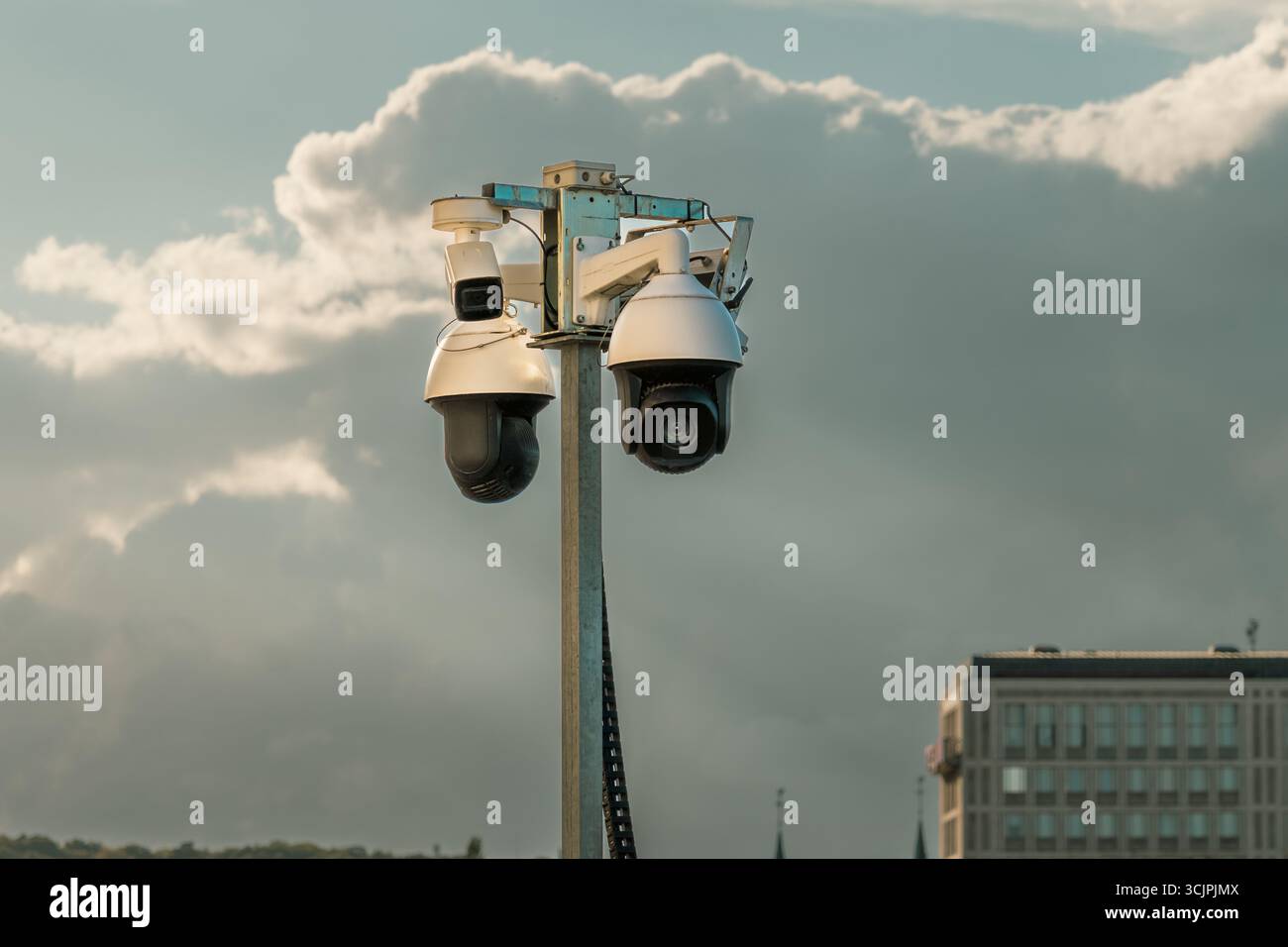 Caméras de surveillance sécurité urbaine Pole City fond. Ensemble de caméras CCTV modernes montées sur un poteau métallique contre un ciel nuageux dans un environnement urbain Banque D'Images